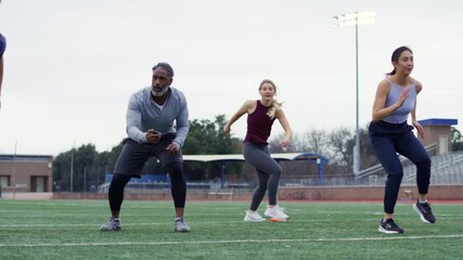 Intense training session on a sports field where athletes practice sprint drills under the watchful eye of a coach. - Powered by Adobe