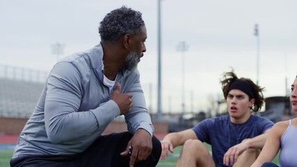 Coach provides guidance and motivation to athletes during an outdoor training session. - Powered by Adobe