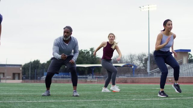 Intense training session on a sports field where athletes practice sprint drills under the watchful eye of a coach.