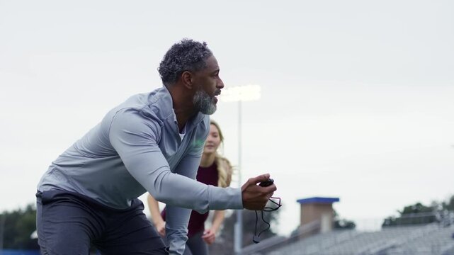 Intense practice session as athletes sprint on the track under the guidance of a focused coach.