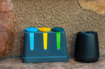 Colorful recycling containers with blue, yellow, and green lids for sorting different types of waste. Concept of environmental protection, ecology, and waste management.