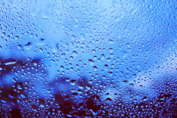 水滴のついた窓越しの青い風景　エモーショナル　ノスタルジック　雨上がり　湿気　背景