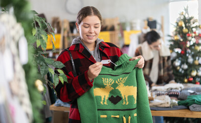 Naklejka premium European girl near showcase pick out and buying pullover. Off line clothing store from retailer. Style and fashion look, modern trends. Discount X mass holiday season, promotional offers.