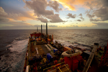 A semi-submersible heavy lift ship underway at sea under dramatic sky