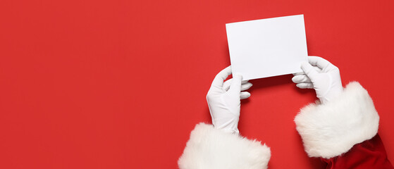Santa Claus hands holding blank card on red background with space for text, top view