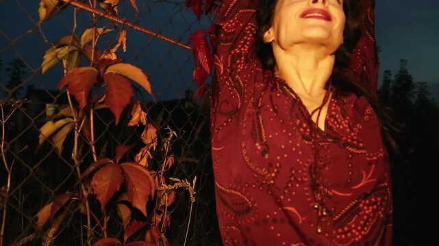 Makeup smling beauty face woman with red lipstick, long brown hair in fashion blouse, posing on the beautiful bright flowers wall on nature red autumn 