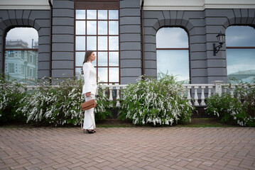 Elegant Businesswoman in White Suit Walking by Modern Building