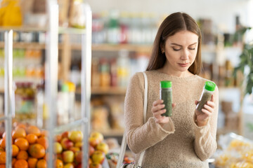 Young woman buyer chooses seasoning herbs in jar in grocery store