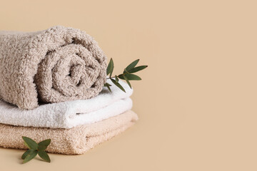 Clean soft towels and green twigs on beige background, closeup
