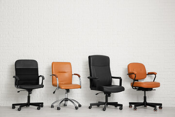 Different office chairs near white brick wall in room