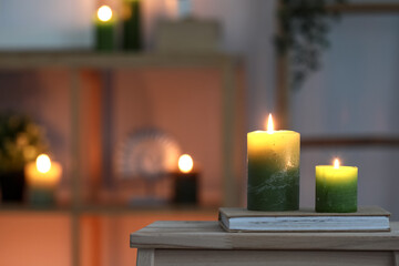 Book and burning candles on table in interior of room, closeup