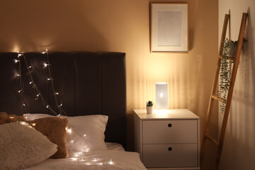 Soft bed, bedside table and glowing lamps in interior of bedroom