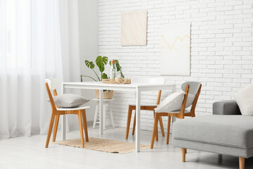 Interior of dining room with sofa, table and chairs near white brick wall