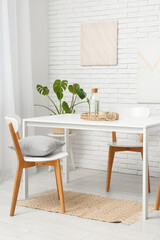 Interior of modern dining room with table and chairs near white brick wall