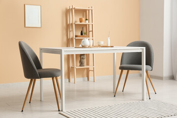 Interior of dining room with table and chairs near beige wall
