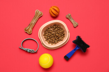 Bowl with dry pet food and accessories on red background