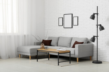 Obraz premium Sofa and coffee table near white brick wall in interior of living room