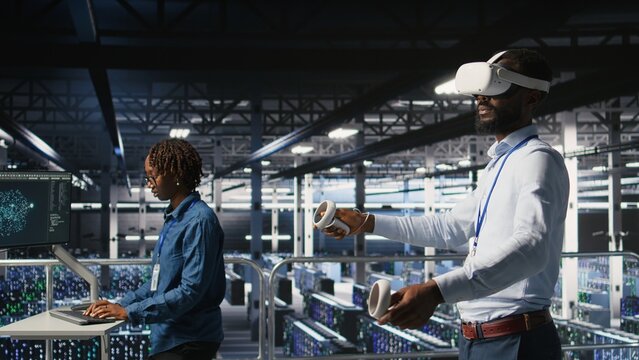 Data center programmers on industrial platform using virtual reality tech, collaborating on tasks. Server room IT professionals visualizing large language model architecture using VR headset