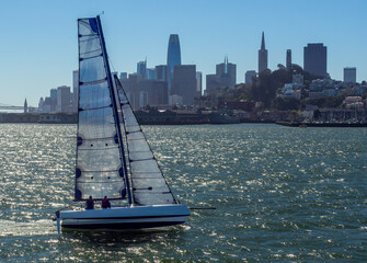 Exciting multihull sailing with carbon fiber sails full of wind in San Francisco Bay with the city in the background on a brisk Spring day.