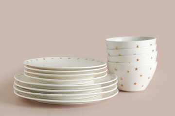 Stacks of clean white dishes on beige background, closeup