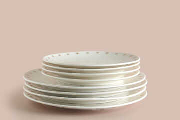 Stack of clean white plates on beige background, closeup
