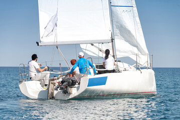 Team of sailors navigating a white yacht on blue sea