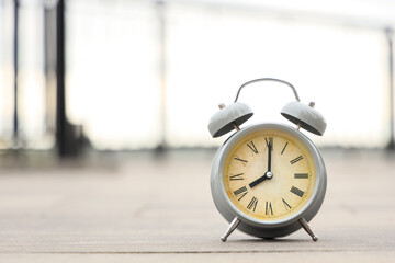 Naklejka premium Grey retro alarm clock on pavement outdoors, closeup