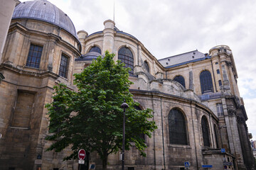 Ancient church building with domes and tree in front under cloudy sky in Paris France © Moiseii Production