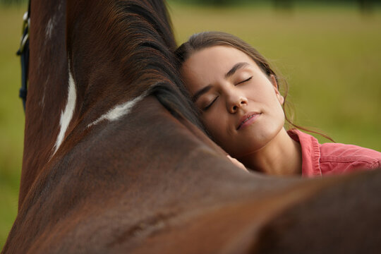 A young woman shares a peaceful moment with her horse in a sunlit pasture - Powered by Adobe