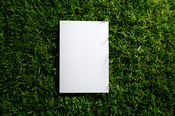 Blank white paper mockup on vibrant green grass perfect for presenting logos, designs, or text