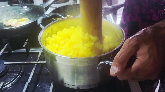 Preparing creamy mashed potatoes with vibrant yellow color on a stovetop