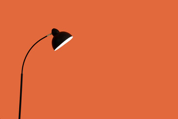 Glowing standard lamp near orange wall