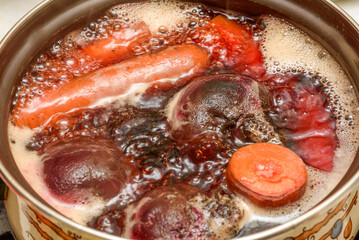 Carrots and beets are cooked in a saucepan in boiling water.