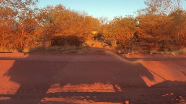 onboard view of a 4x4 offroad travel vehicle driving along a red dirt gravel road through the iconic desert of the outback at Karijini national park in the Pilbara, western Australia.