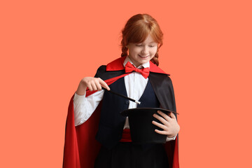 Young magician showing magic trick with hat on orange background © Pixel-Shot