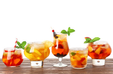 Glass of cold tea with different fruit slices, berries and mint leaves on white background