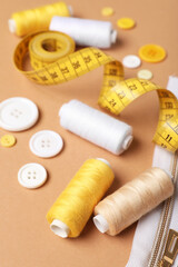 Composition with thread spools and buttons on beige background, closeup