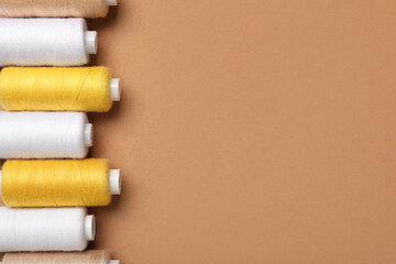 Set of different thread spools on brown background, closeup