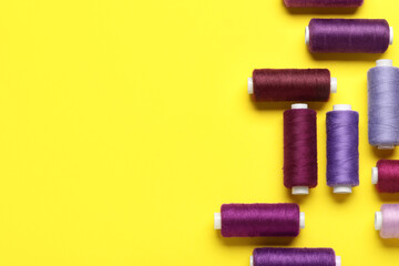 Set of different thread spools on yellow background