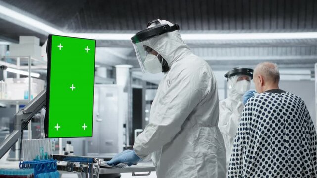 Vertical green screen next to black medic in hazmat suit observing contagious epidemic in lab, examining patient with serious symptoms. Preventing global disaster and health crisis. Camera B.