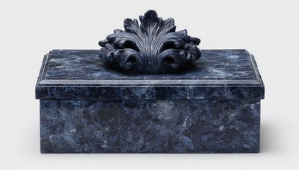 A rectangular dark-blue marble box with a carved foliate ornament on its lid, showcasing swirling veining in the stone.  The box has a subtly beveled rectangular shape