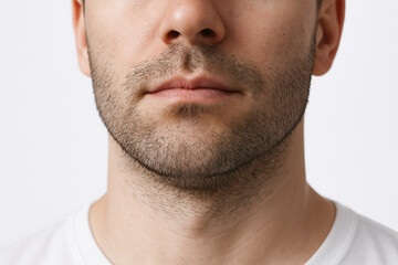 Obraz premium Close-up of male chin with stubble and minimalist white shirt background. concept of masculine style, facial hair detail, minimalist portrait.