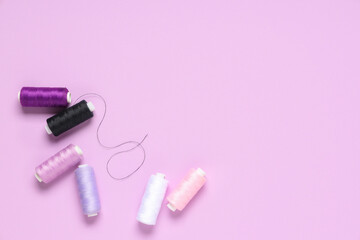 Naklejka premium Different thread spools on lilac background