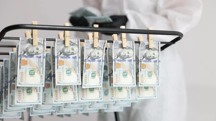 Money laundering. Woman counting dollars near drying rack with banknotes indoors, selective focus
