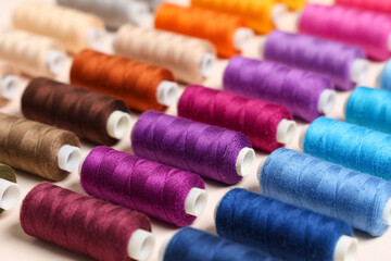 Many different thread spools on beige background, closeup