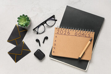 Naklejka premium Notebook with 2026 goals, eyeglasses, earphones and envelopes on grunge background