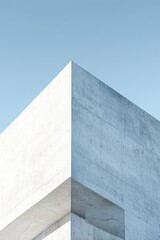 Minimalist architectural detail of a light grey concrete building corner against a clear, pale blue sky.  The image showcases clean lines and a modern aesthetic