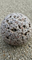 Close up of a textured spherical rock on a gravel surface.