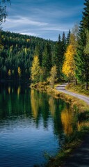 Serene autumnal landscape featuring a calm lake reflecting a winding road and vibrant yellow-gold trees against a backdrop of dark evergreens and a partly cloudy sky
