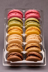Colorful macarons stacked in transparent plastic box
